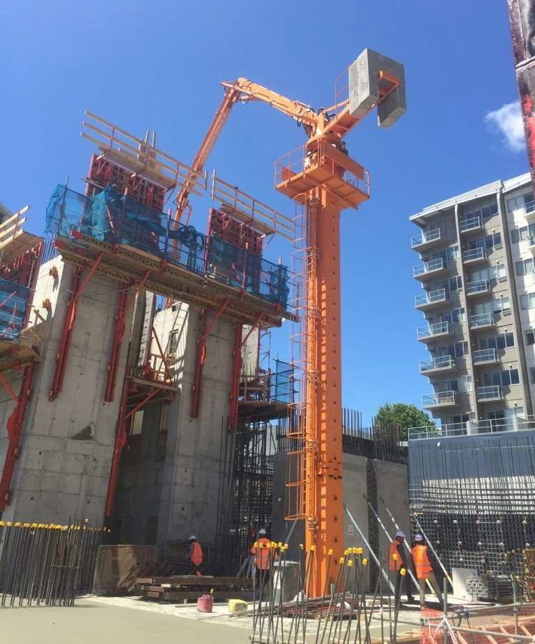 A large orange crane is sitting in front of a building under construction.