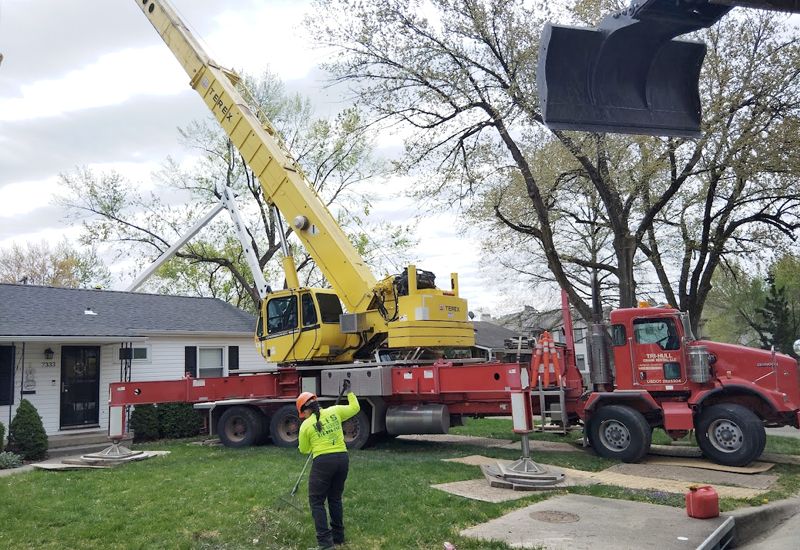 A yellow crane is sitting on top of a red truck in front of a house.