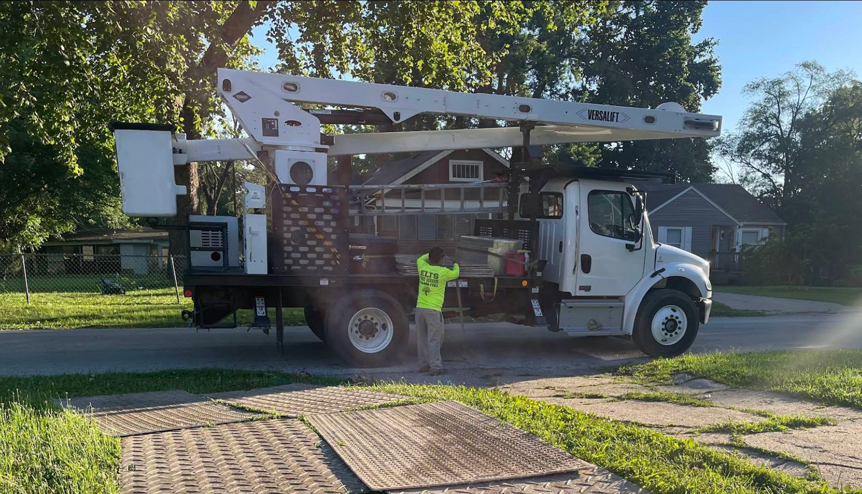 A man is standing next to a large truck parked on the side of the road.
