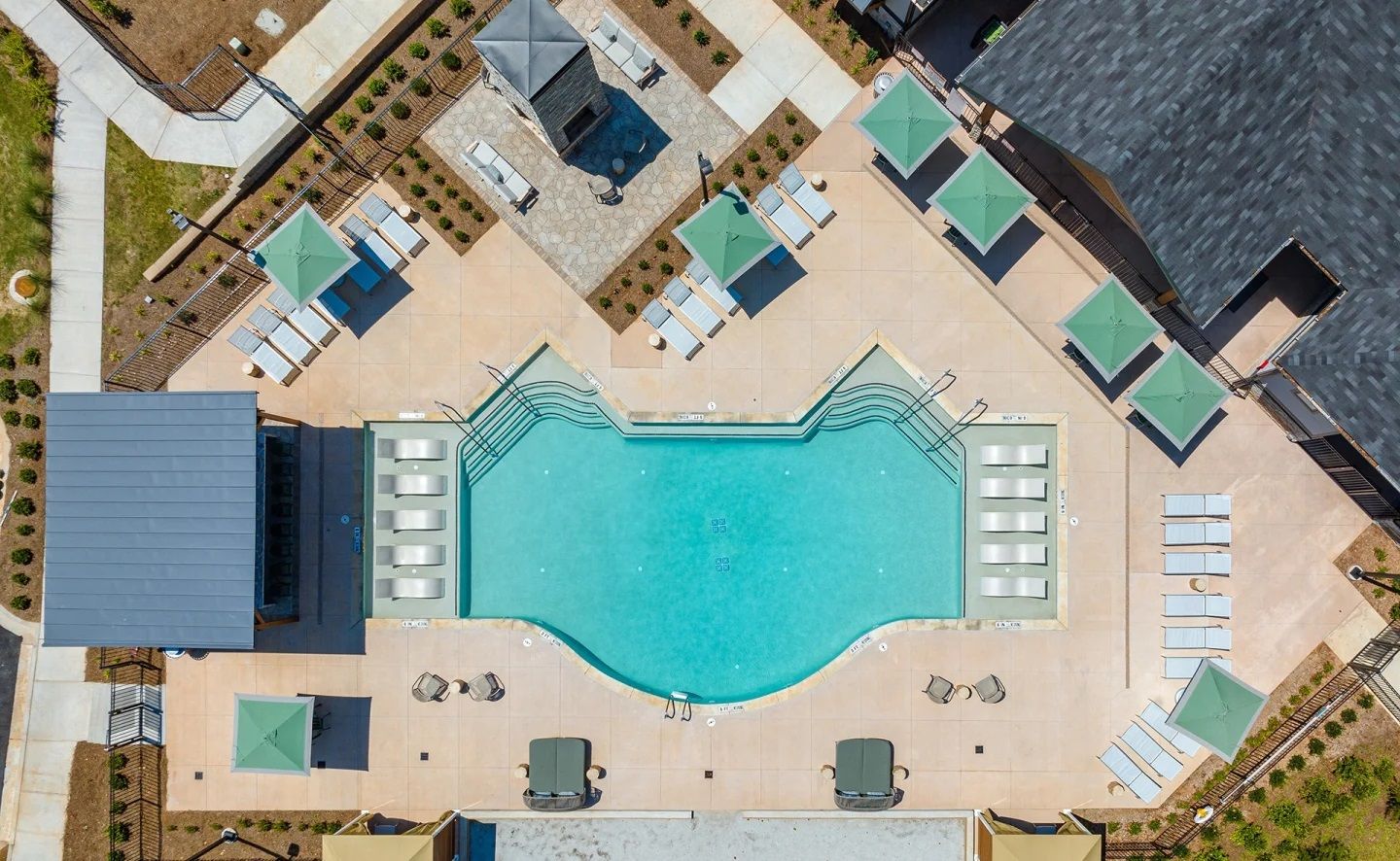 An aerial view of a large swimming pool surrounded by chairs and umbrellas