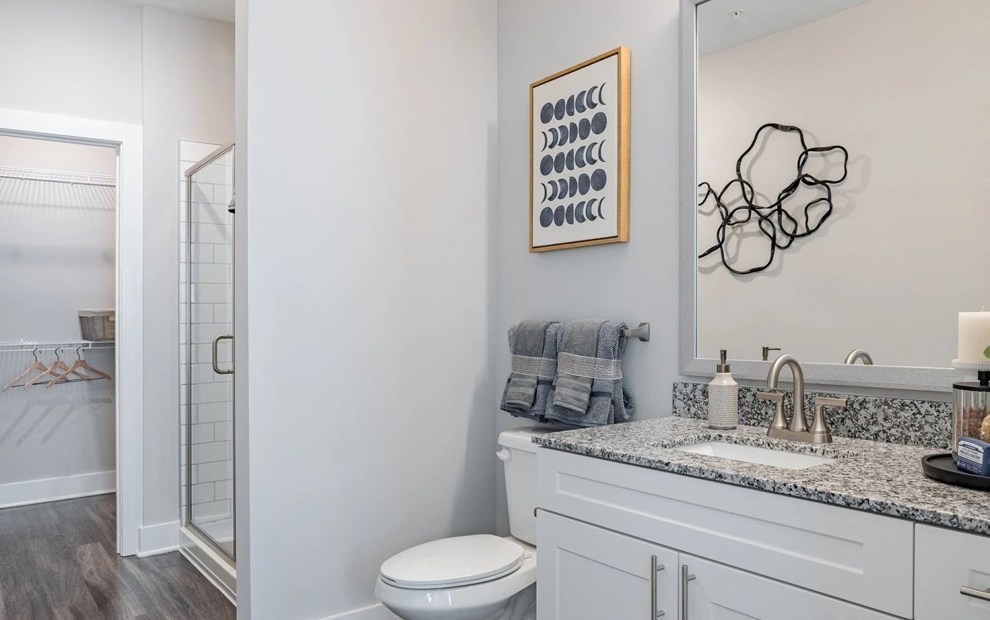 A bathroom with a toilet , sink , mirror and walk in shower.