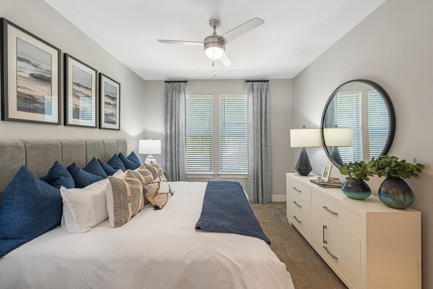 A bedroom with a bed , dresser , mirror and ceiling fan.