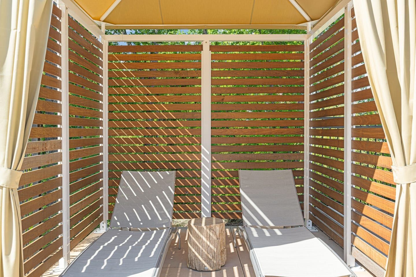 A gazebo with wooden slats and white curtains
