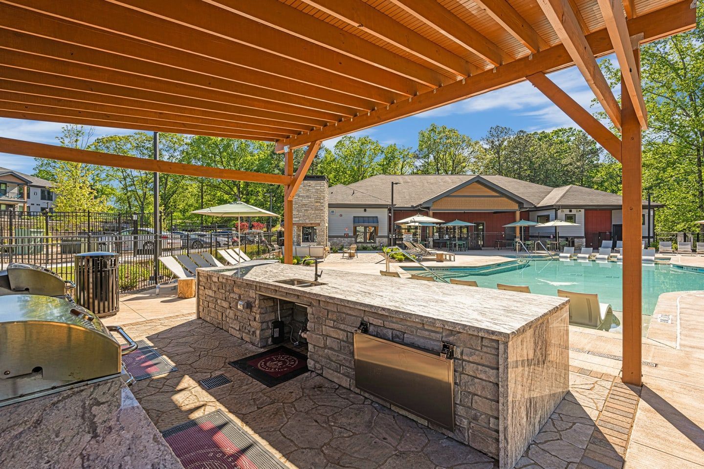A large swimming pool with a kitchen under a pergola