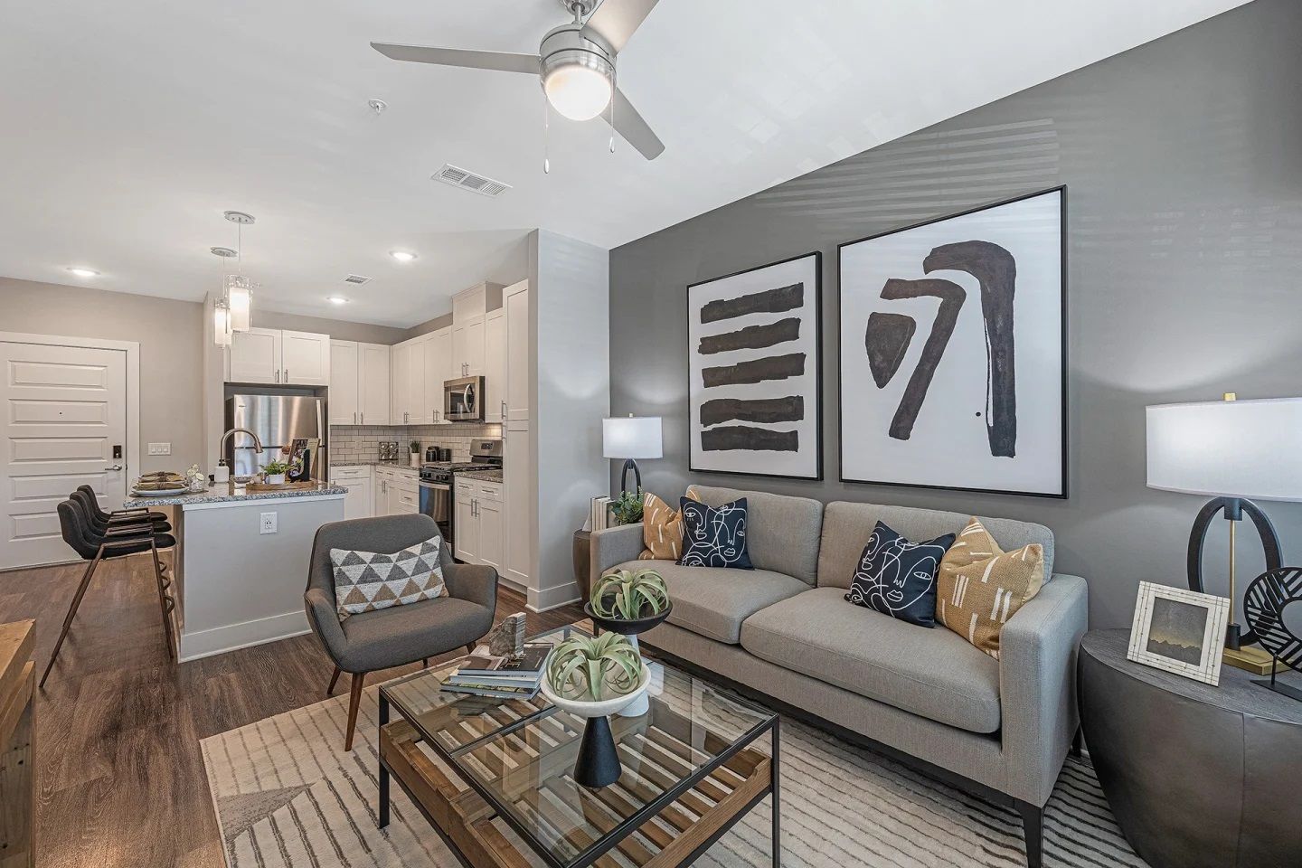 A living room with a couch , chair , coffee table and ceiling fan.