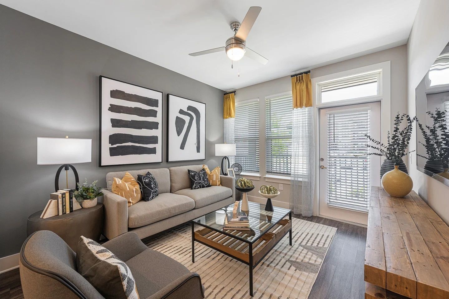 A living room with a couch , chair , coffee table and a ceiling fan.