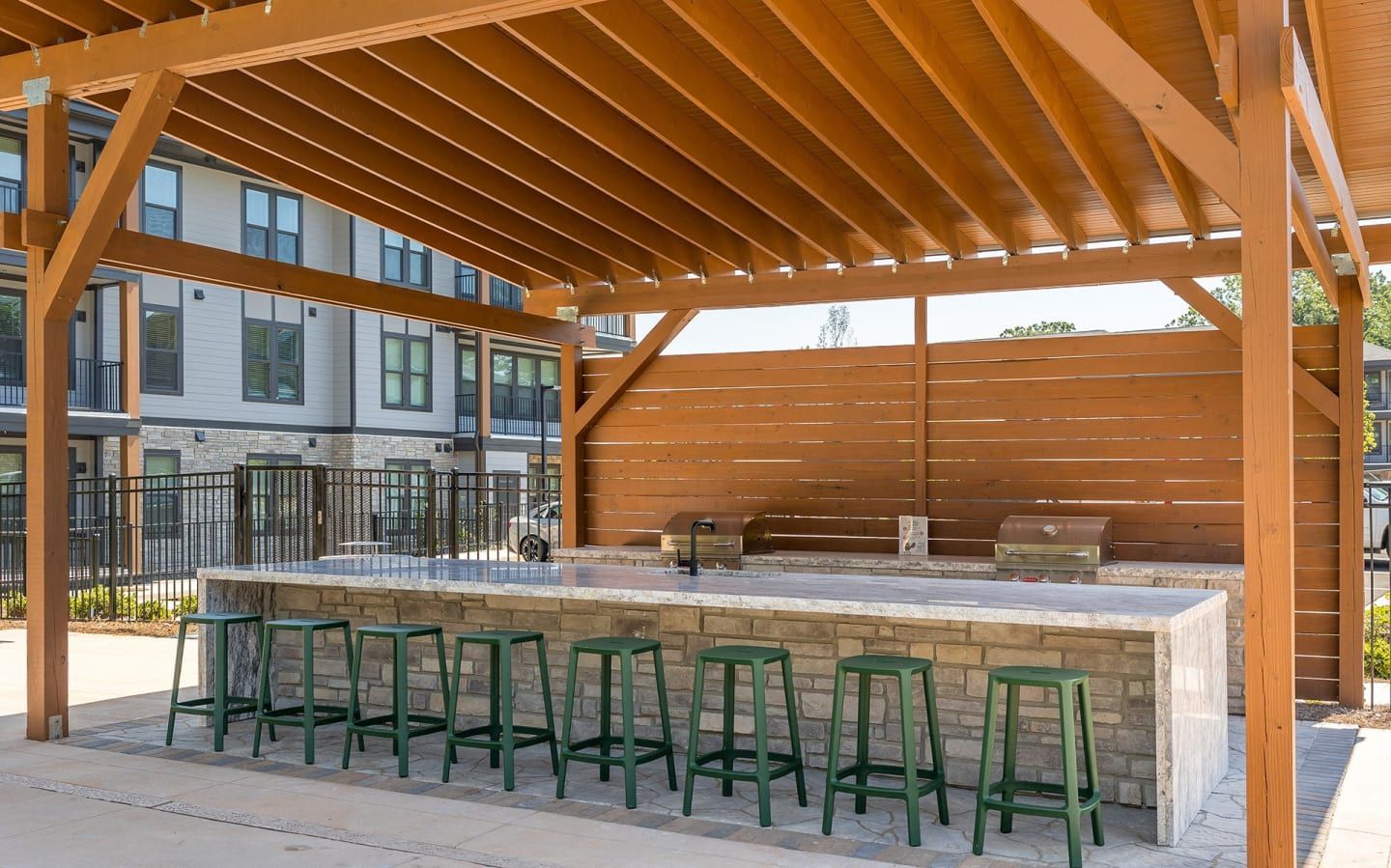 A row of green stools are lined up under a wooden structure