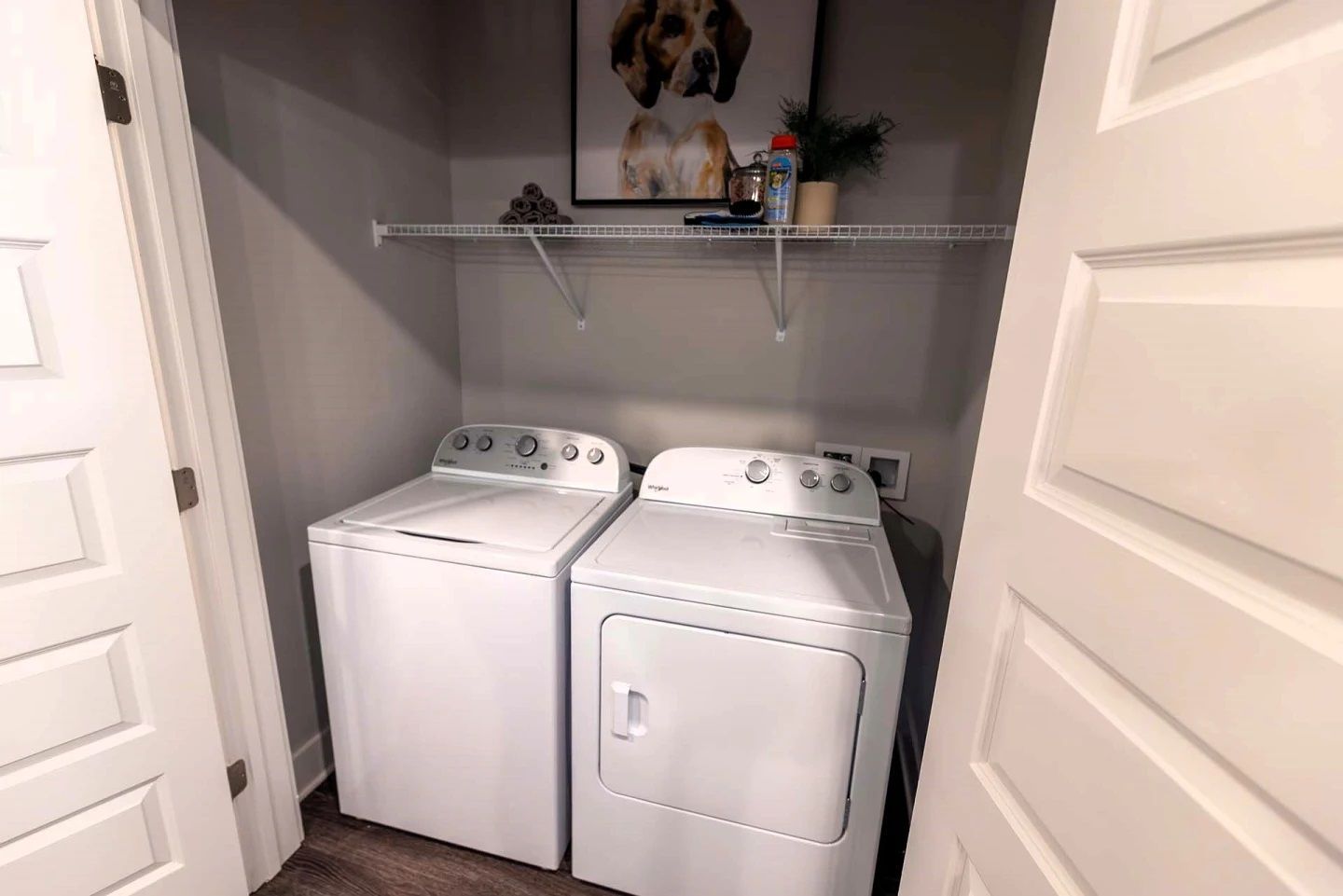 A laundry room with a washer and dryer and a picture of a dog on the wall.