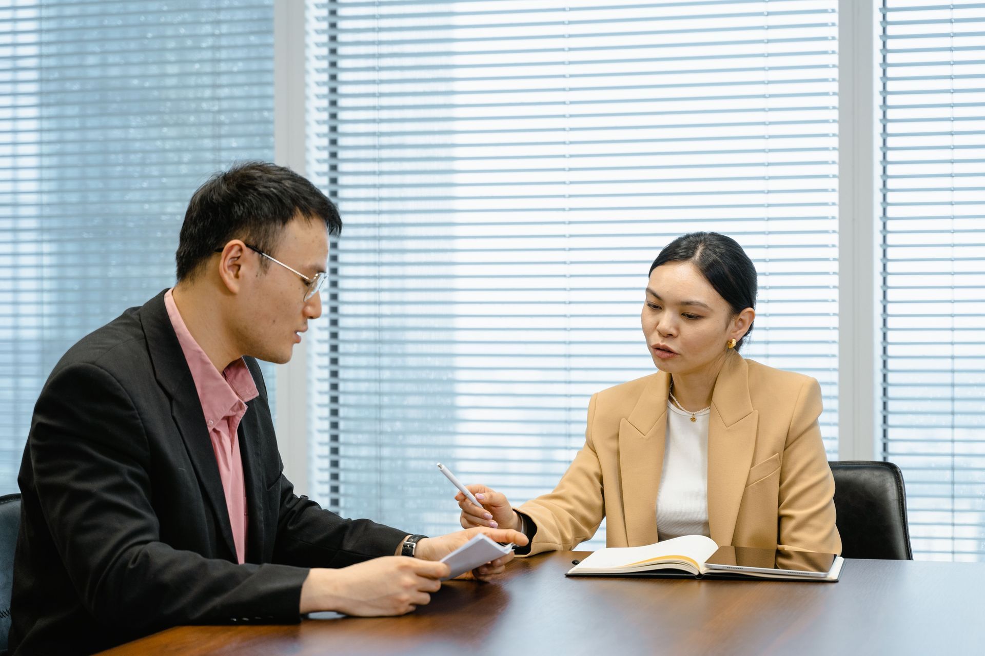 A man and a woman are sitting at a table looking at a laptop.