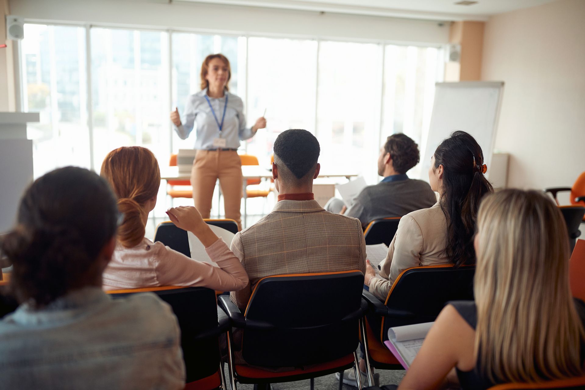 A woman is giving a presentation to a group of people in a classroom.