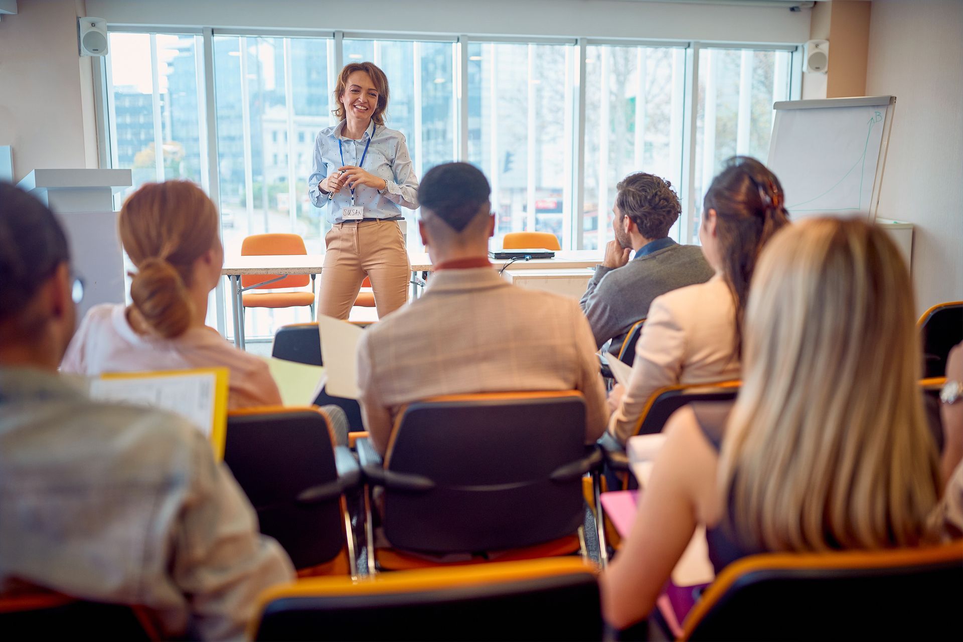A woman is giving a presentation to a group of people in a classroom.