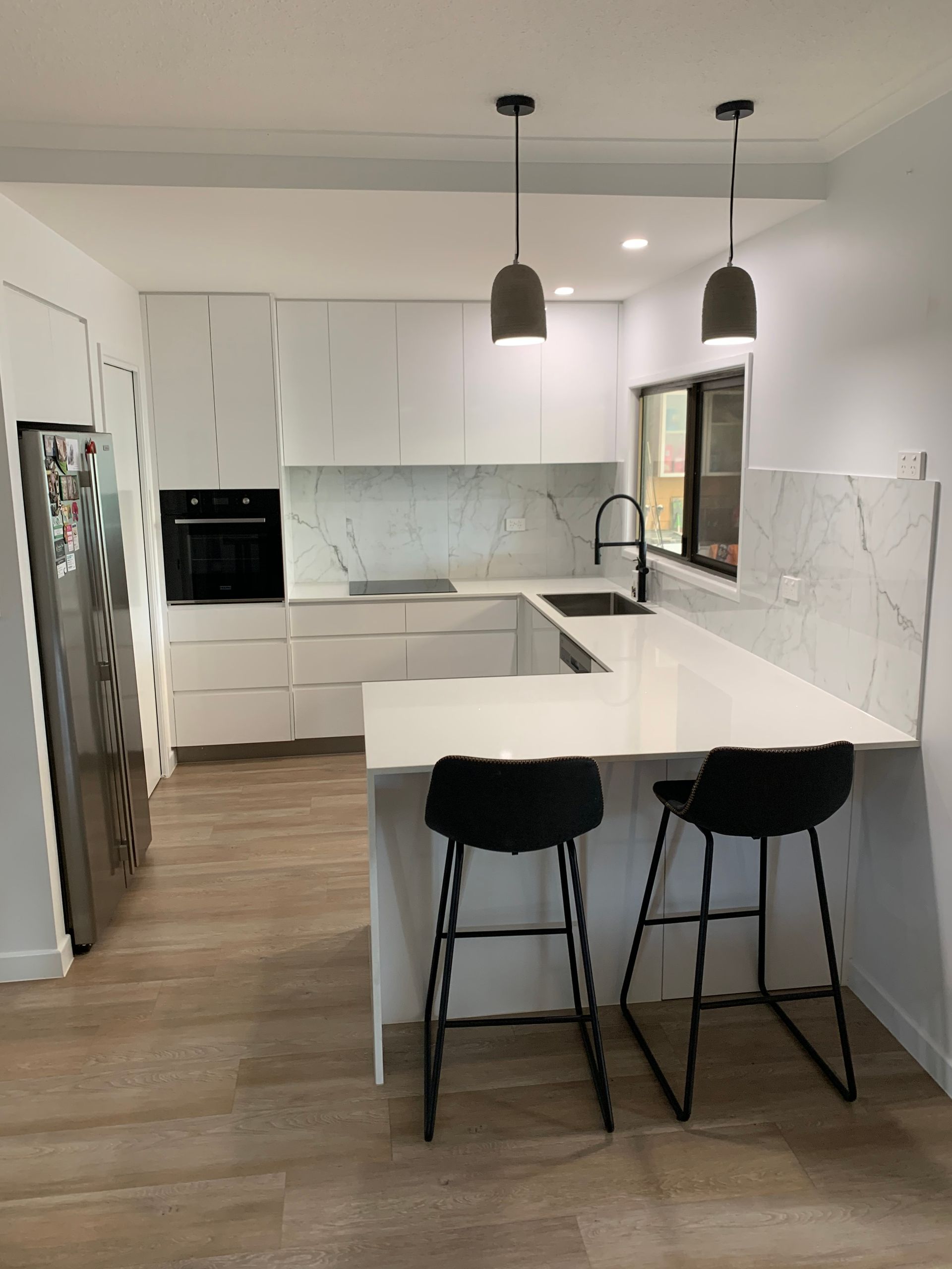 Kitchen with white cabinet and marble splashback and black chairs