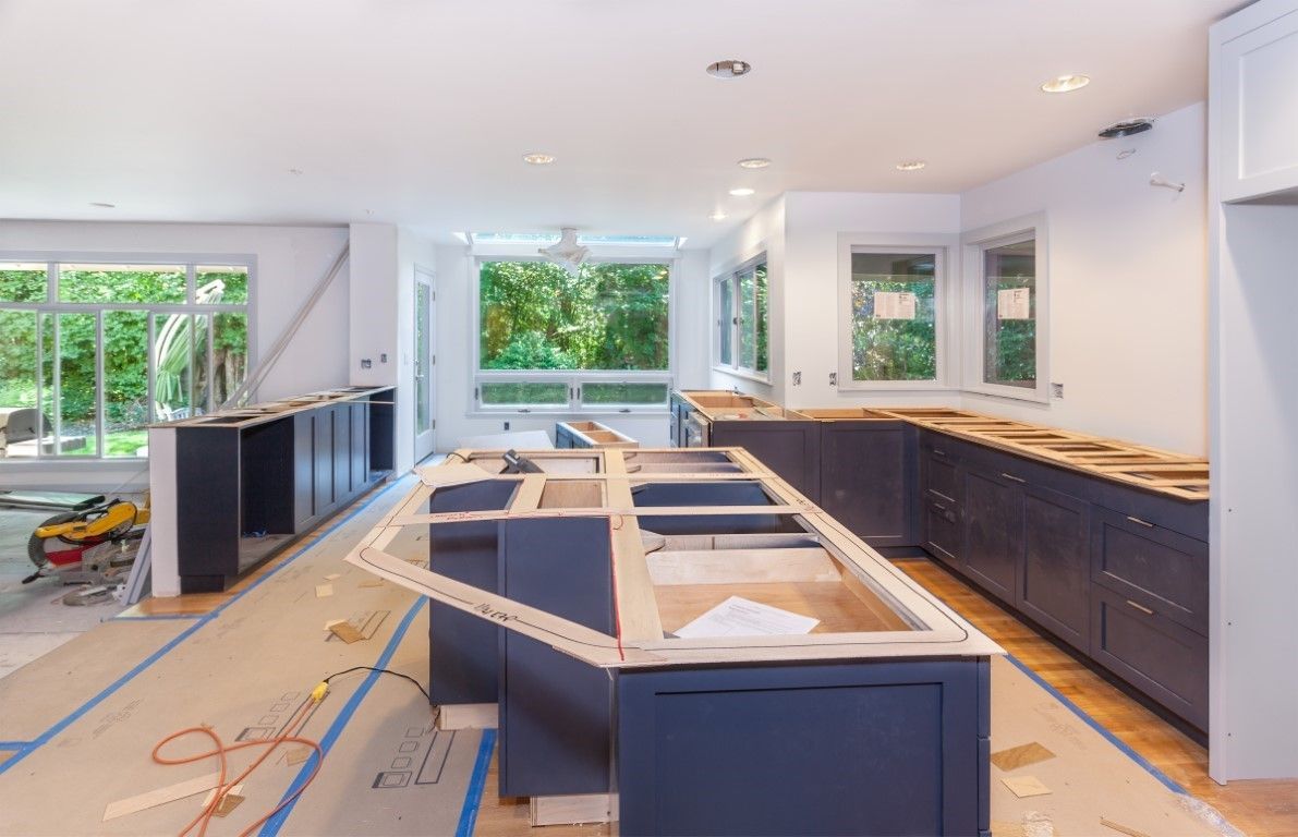 Modern white kitchen with gold-veined marble island, brass lighting fixture, and stainless steel appliances.