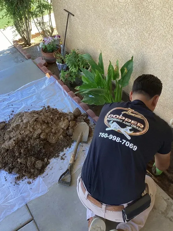 Under-sink plumbing with exposed pipes, valves, and a wrapped drain hose during repair
