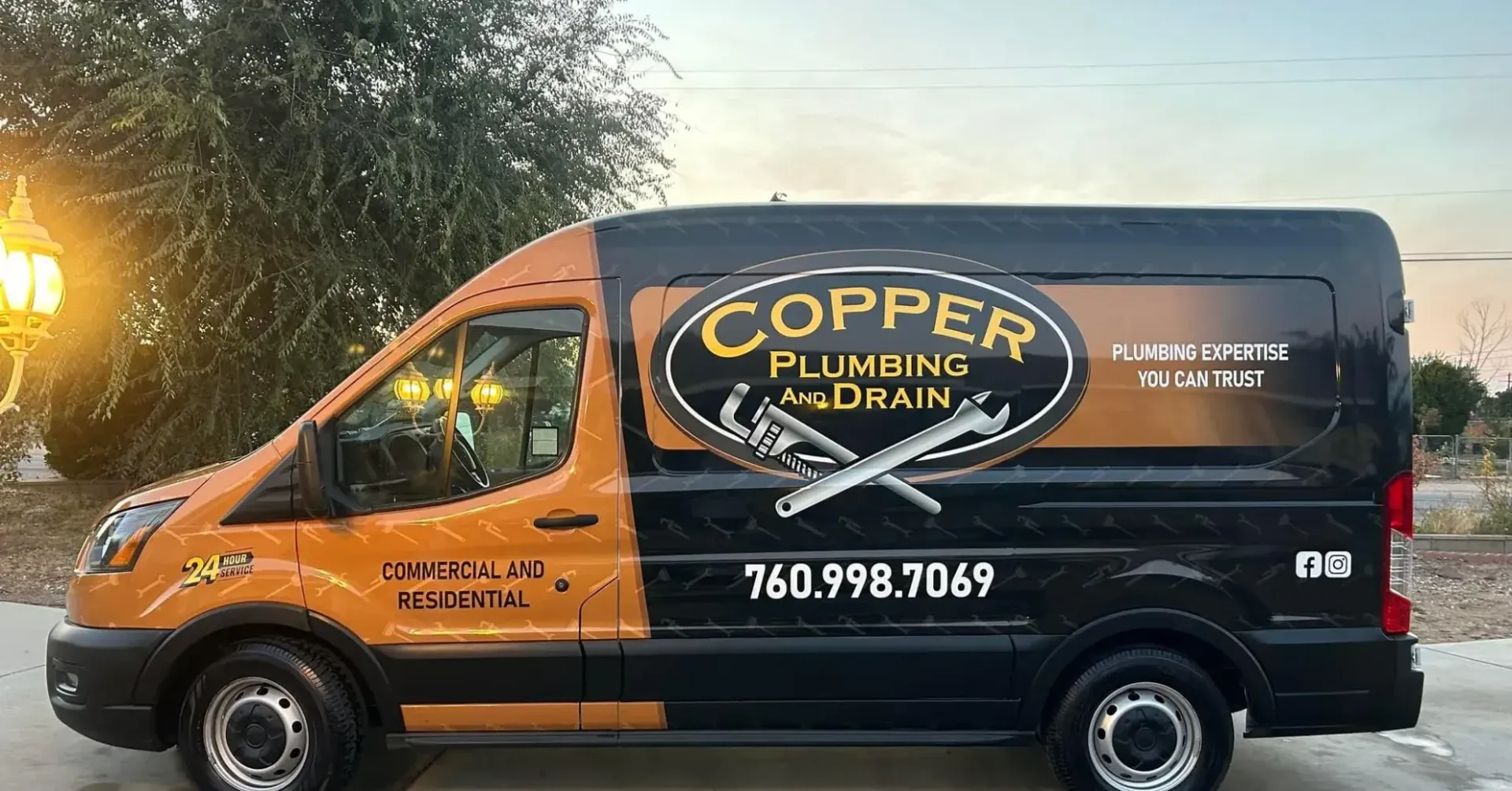 Copper Plumbing & Drain service van parked outdoors at dusk, orange and black, with company logo and phone number.