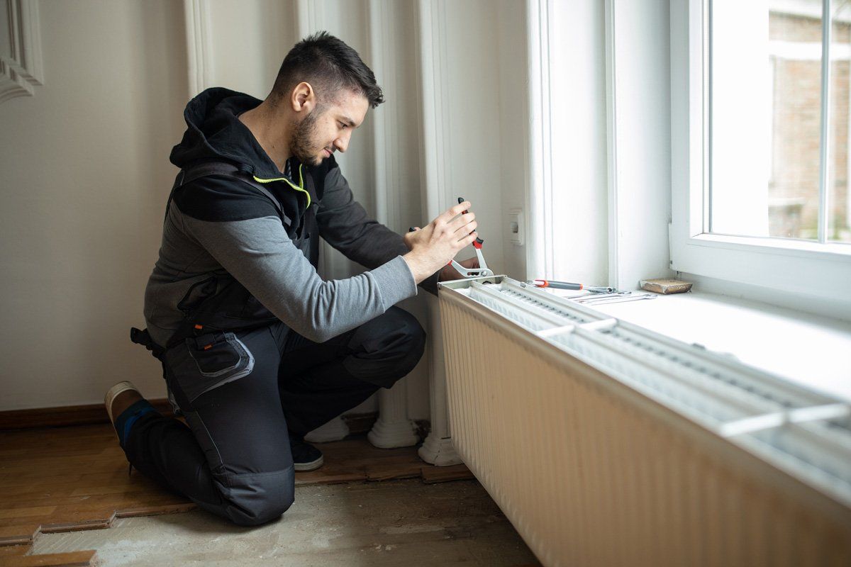 Man Installing an Air Conditioning in a House — Lincoln, NE — Service Techs Man Installing an Air Conditioning in a House — Lincoln, NE — Service Techs