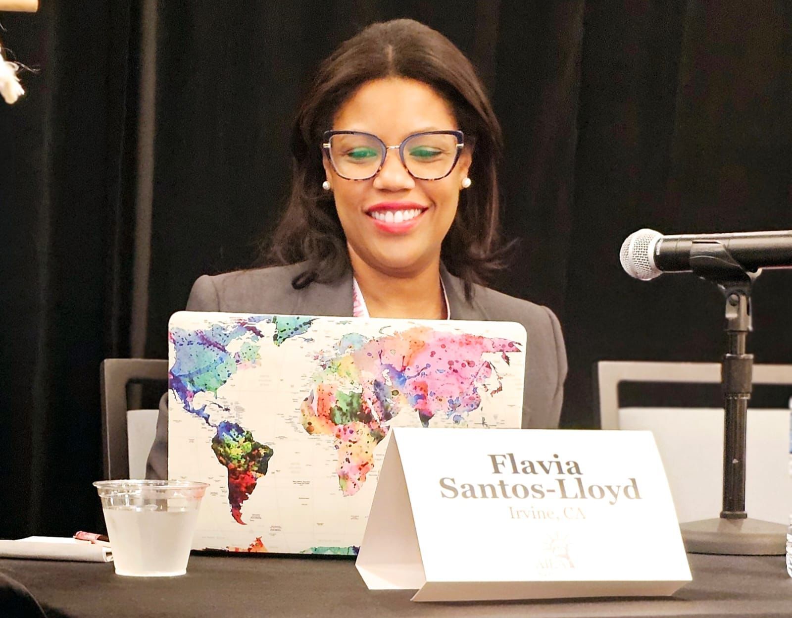 People clapping in a conference room. Woman with afro smiles. Others applaud and smile.