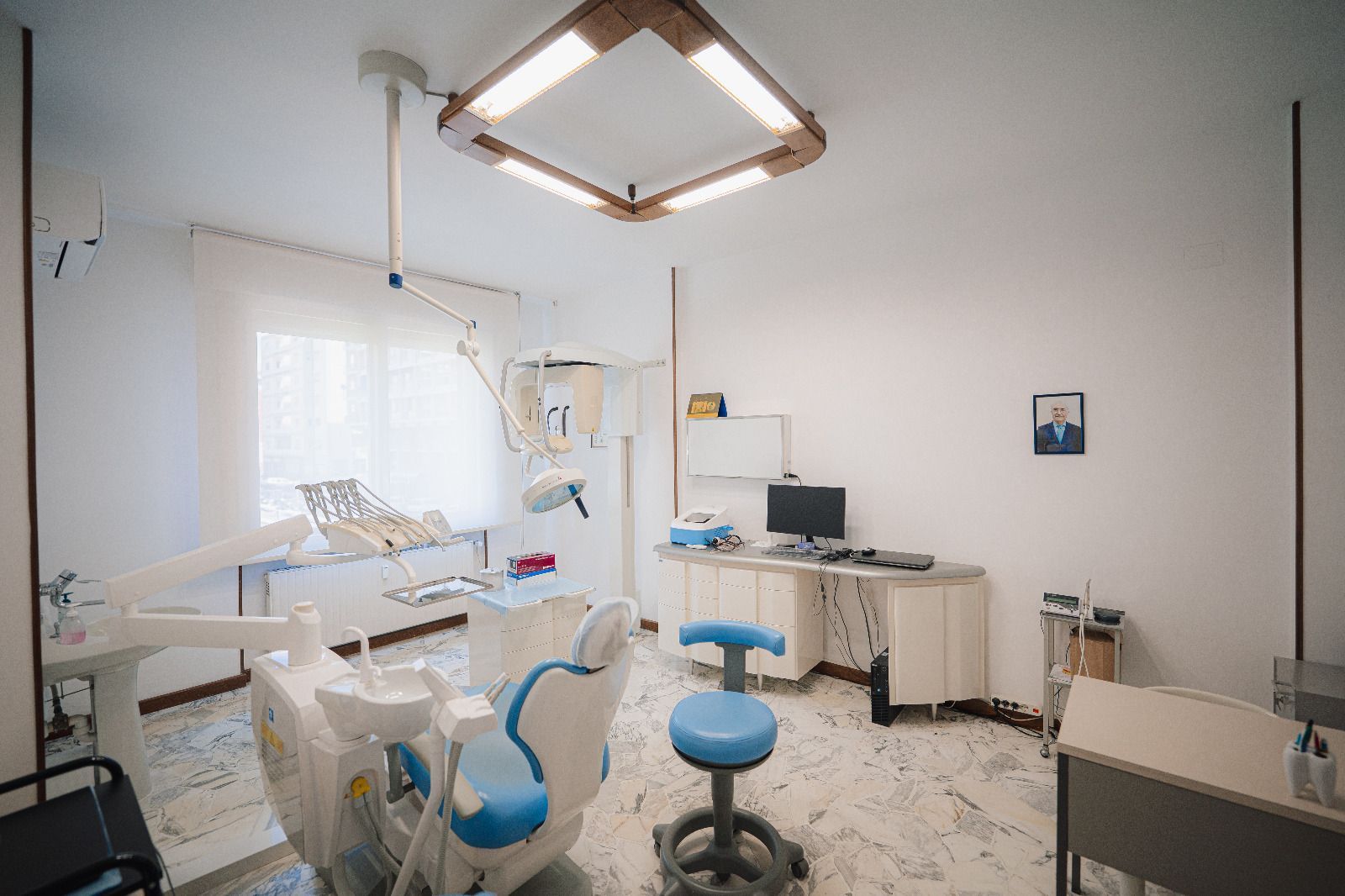 Sala odontoiatrica vuota con sedia, sgabello, armadietti e lampada a soffitto.