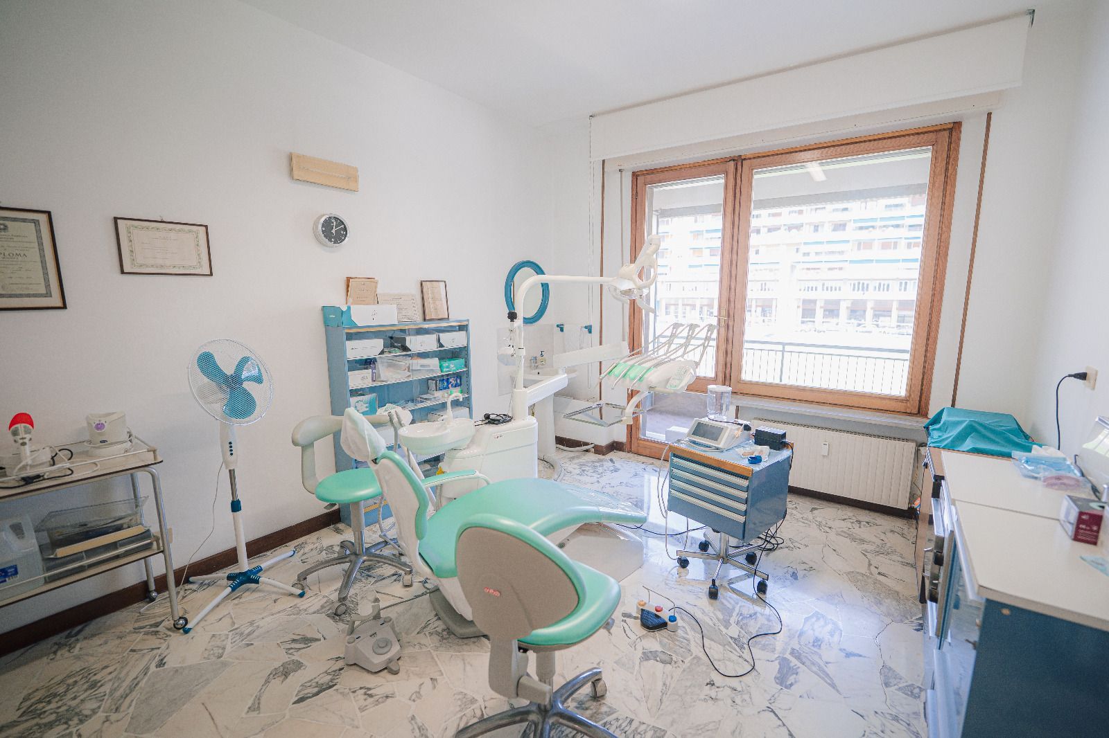 Sala visite odontoiatriche vuota con poltrona verde menta, strumenti e una grande finestra