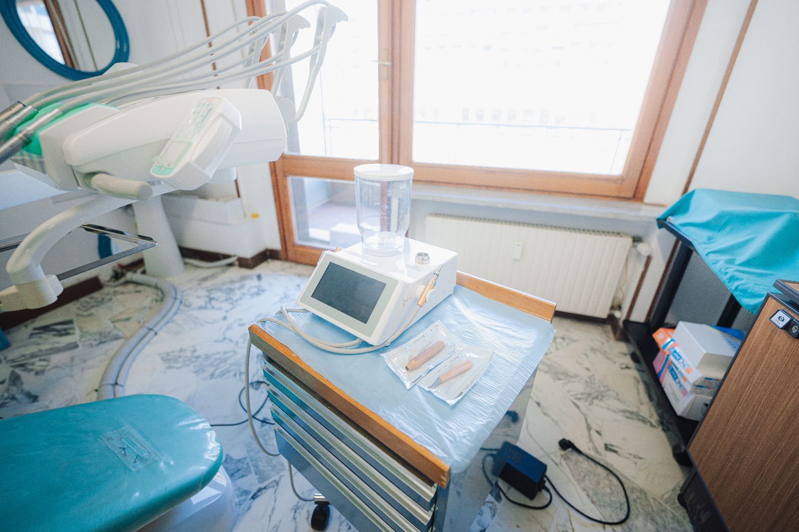 Studio dentistico con poltrona, attrezzatura e monitor in una stanza luminosa.