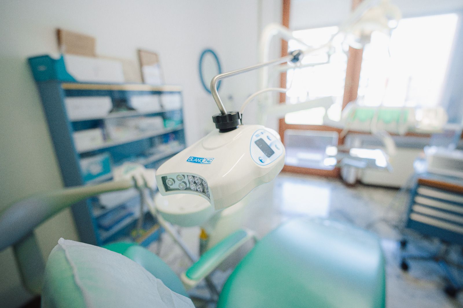 Stanza d'ospedale con un dispositivo medico in primo piano e un letto di paziente sullo sfondo.