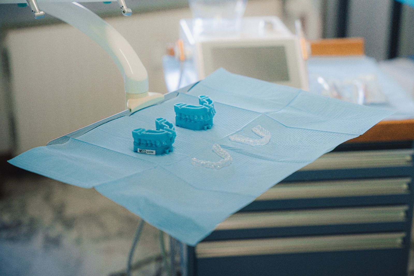 Due modelli dentali blu stampati in 3D su un bavaglino protettivo blu in uno studio dentistico.