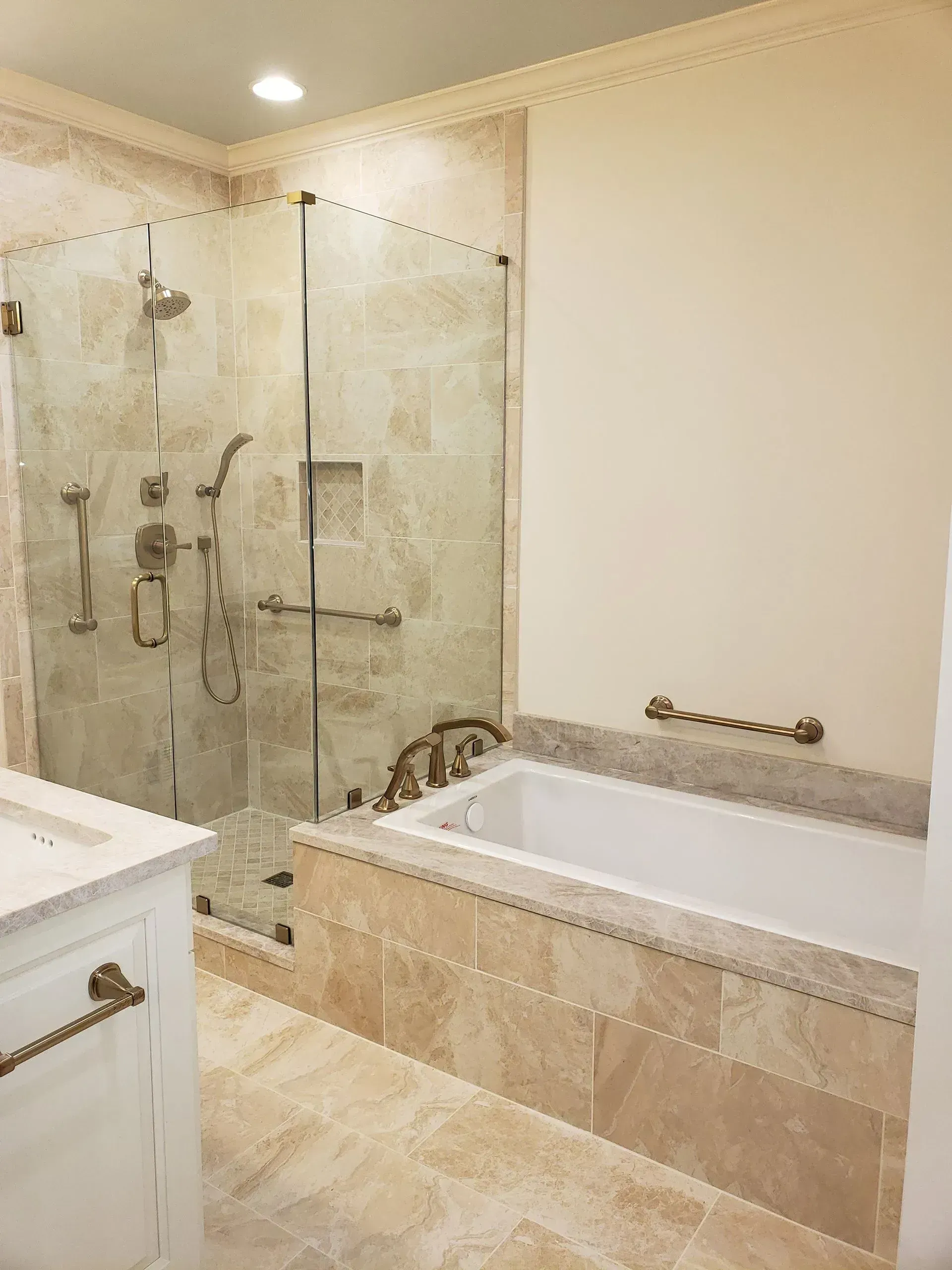 Luxurious beige bathroom with glass shower, soaking tub, and marble tile flooring