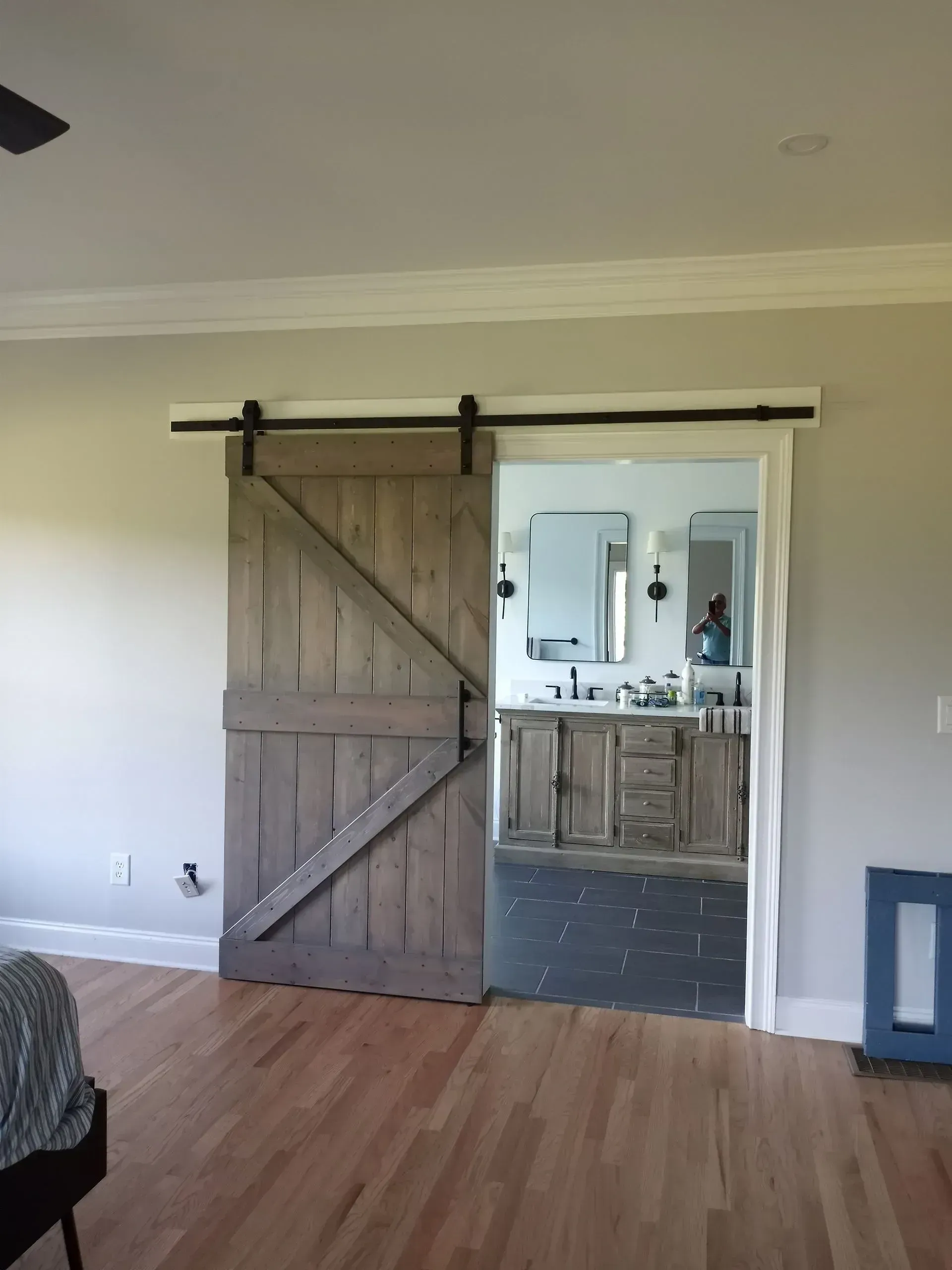 Empty room with wood floor and sliding barn door opening to a bathroom vanity