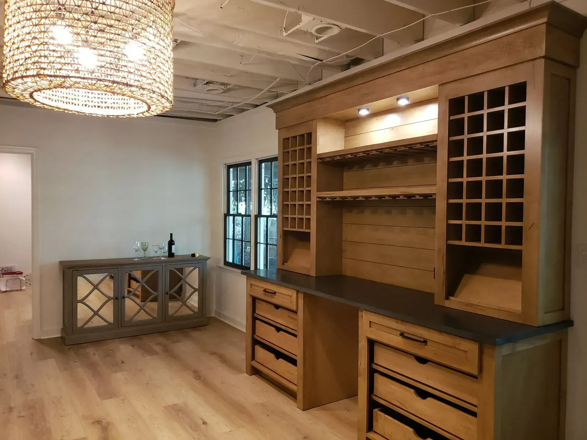 Empty room with built-in wood bar cabinetry, hanging light fixture, and hardwood floors