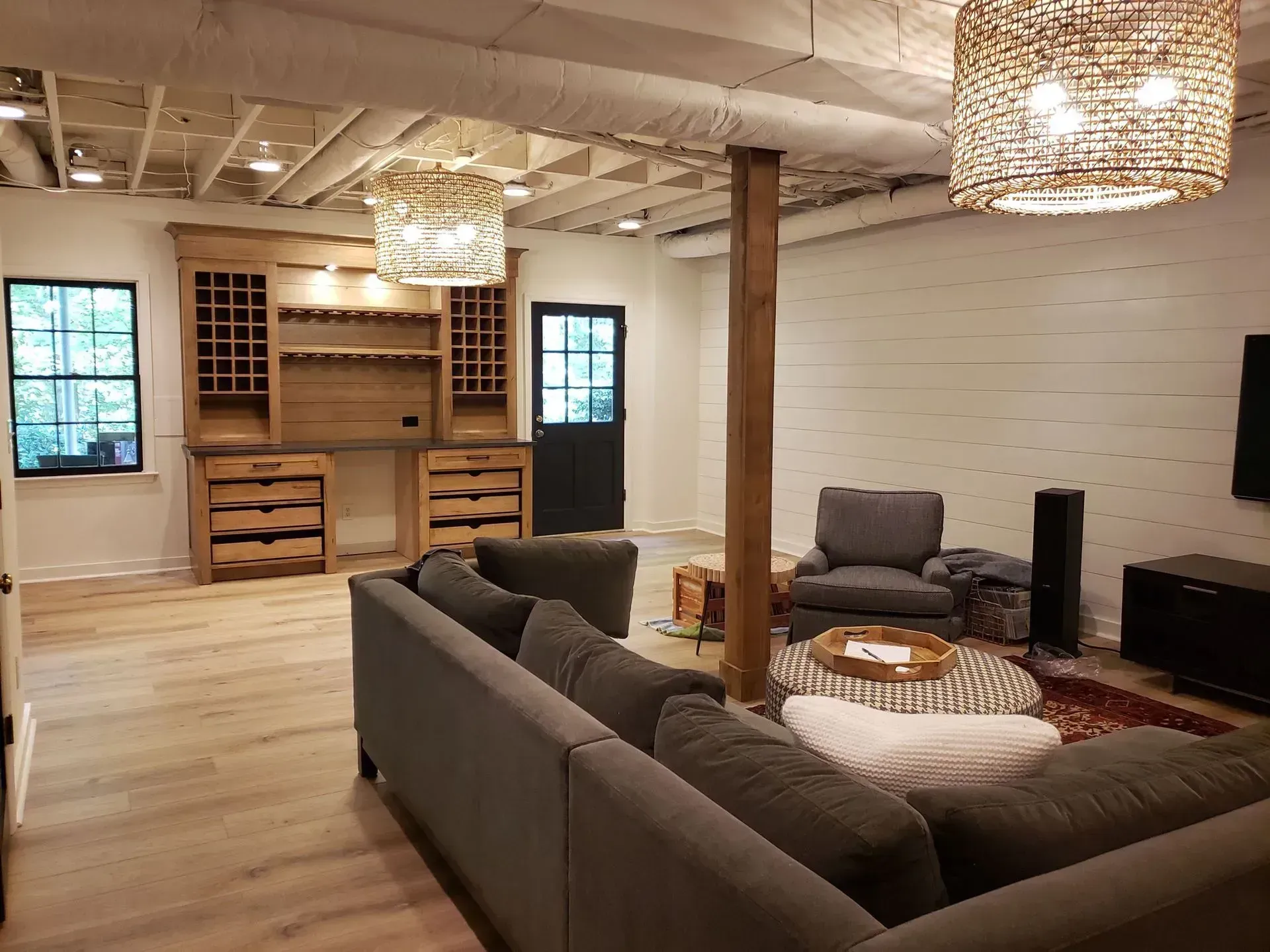 Spacious open living room with gray sectional, wood floors, exposed beams, and built-in shelving