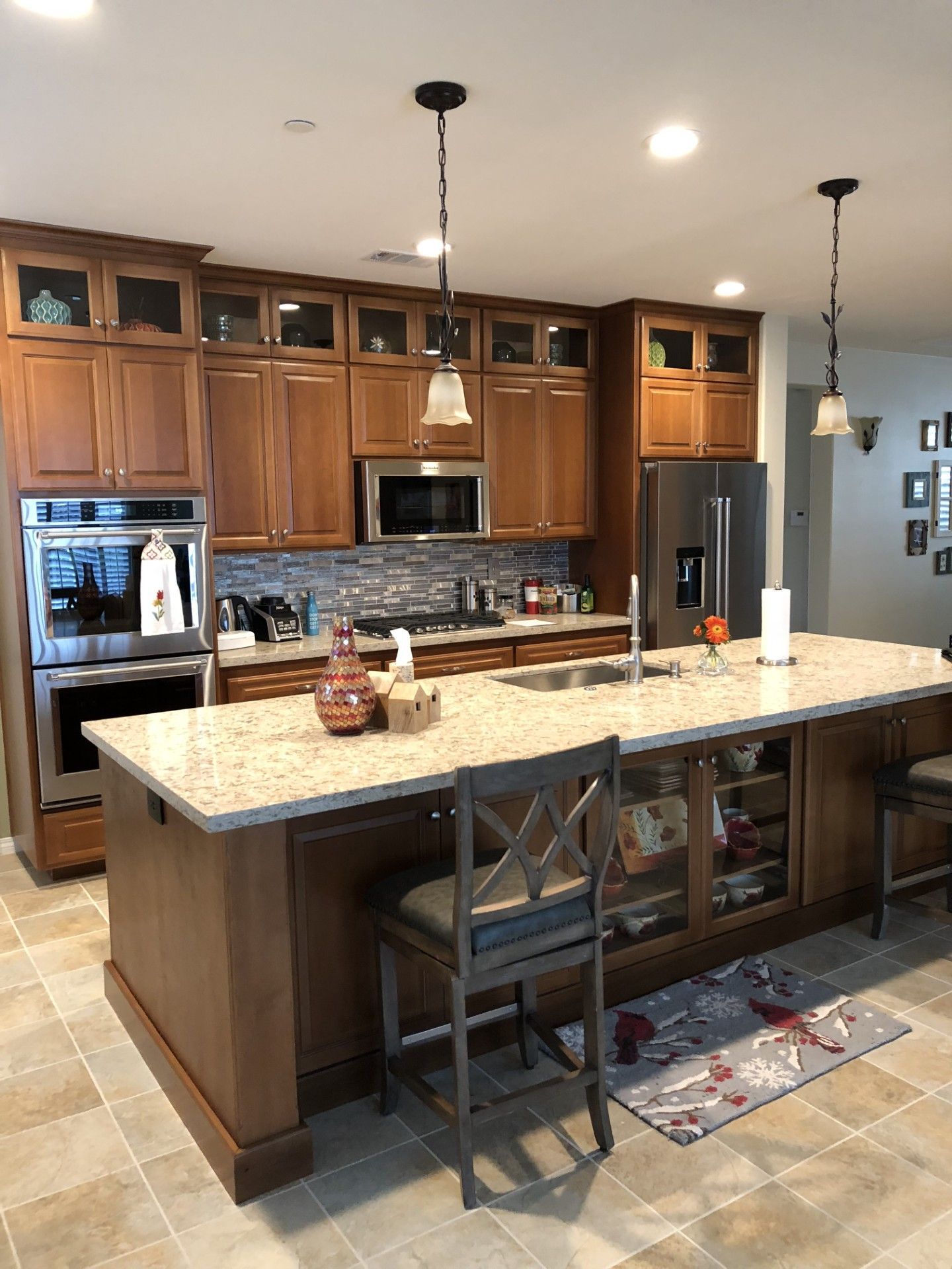 A kitchen with wooden cabinets , granite counter tops , stainless steel appliances and a large island.