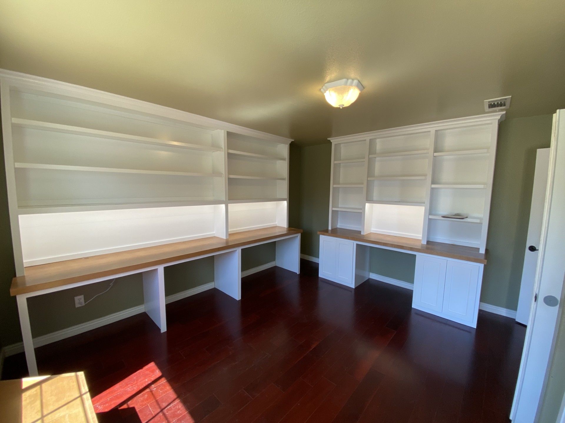 A room with two desks and shelves in it.