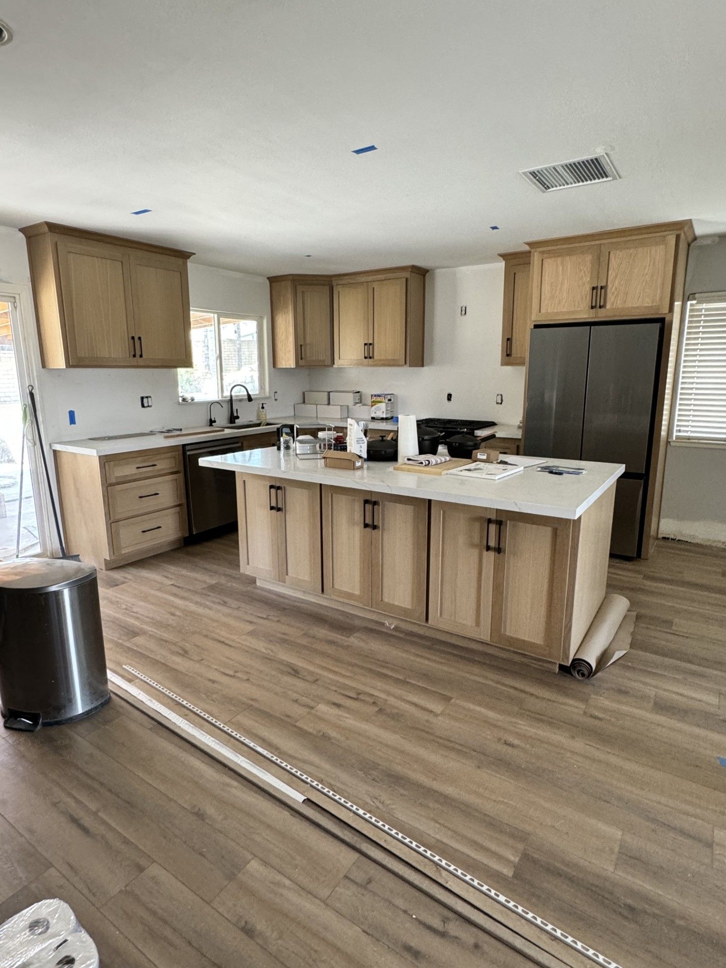 A kitchen with wooden cabinets and a large island in the middle.