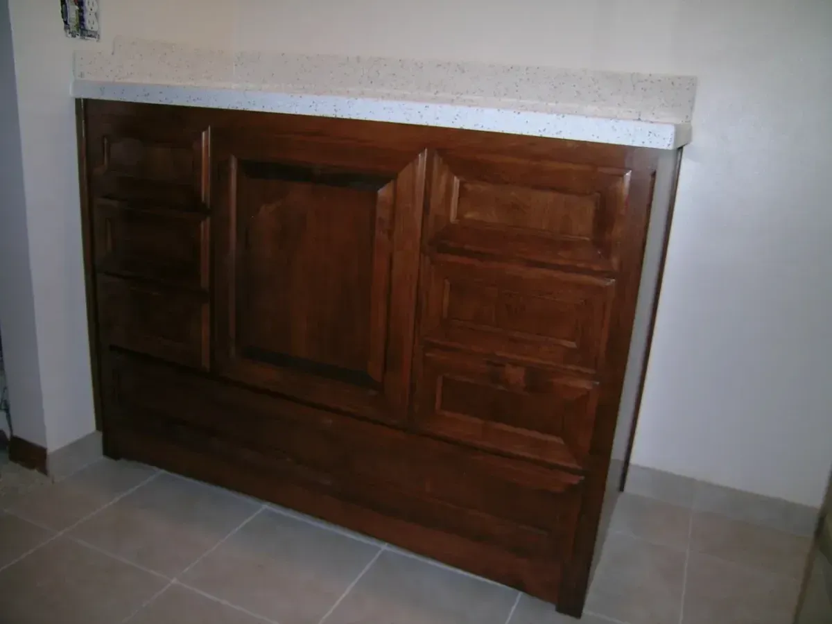A wooden cabinet with drawers and a white counter top