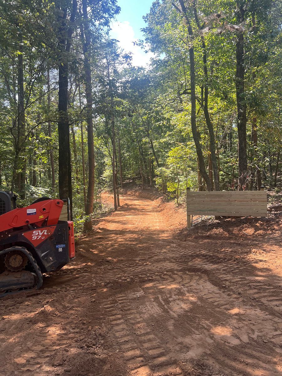 Wooded trail with a red ATV on the left and a wooden bench on the right