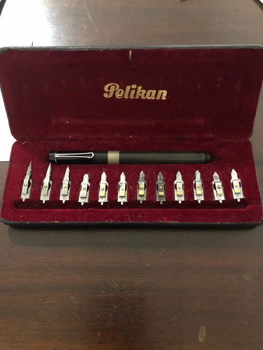 Pelikan pen set in red velvet box with one black pen and multiple nibs on a wooden table