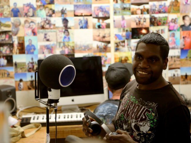 A man wearing a shirt that says avenues is standing in front of a microphone