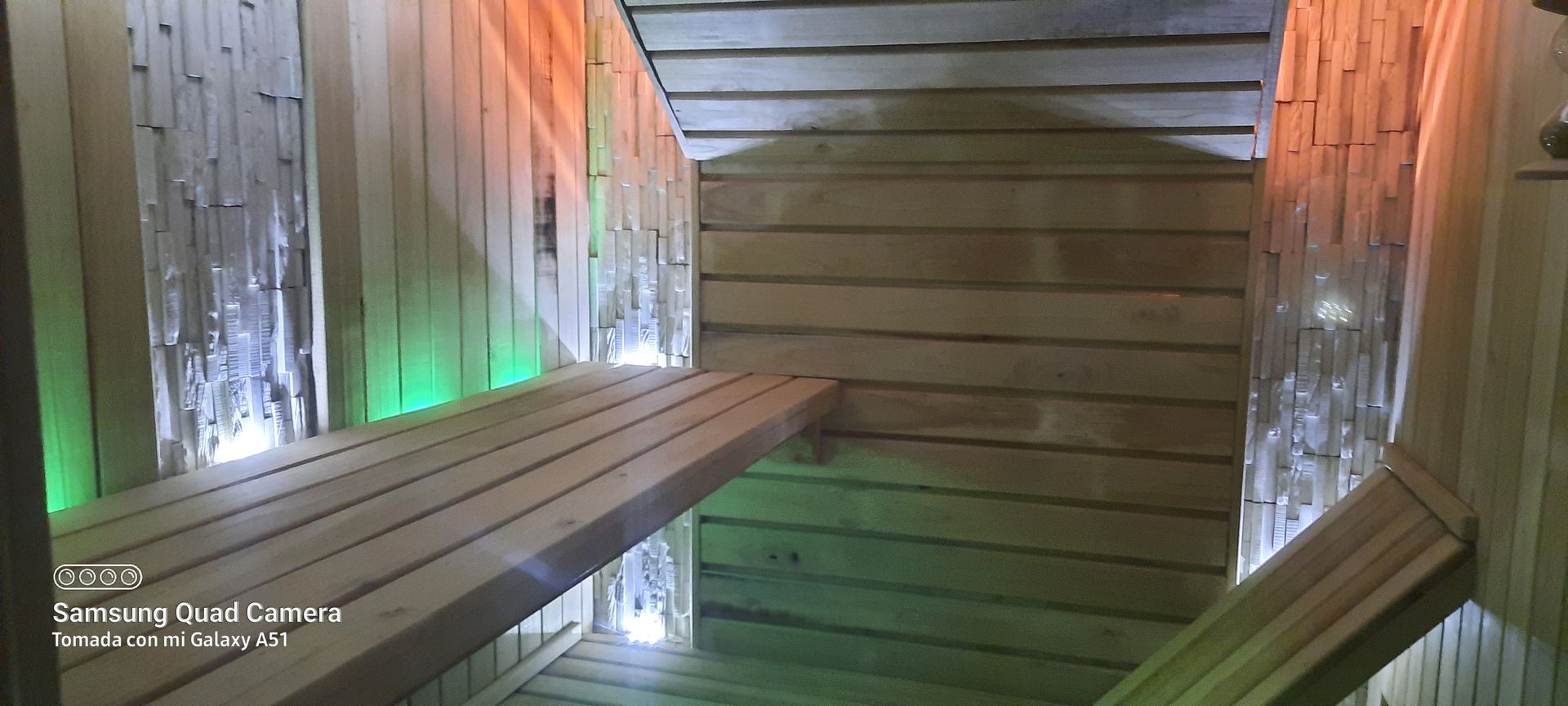 A wooden sauna with a bench and lights on the walls.