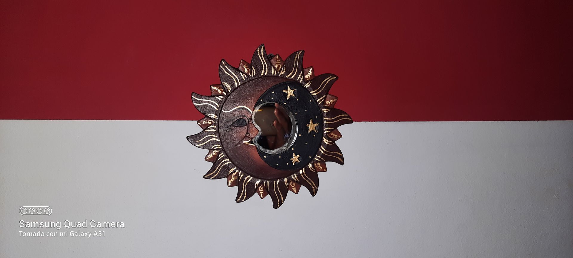 A picture of a sun and moon on a red and white wall.