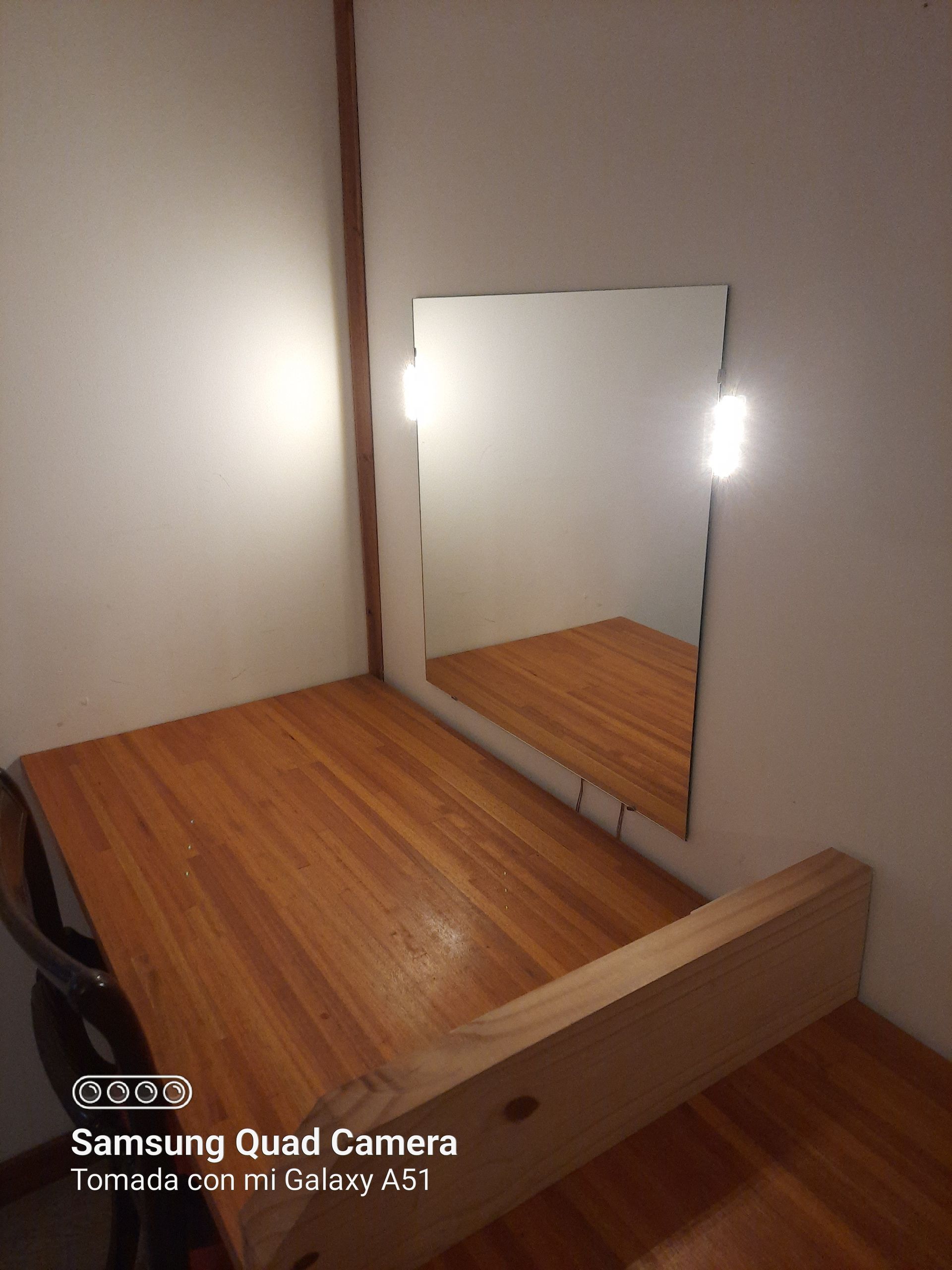 A samsung quad camera takes a picture of a wooden desk and mirror