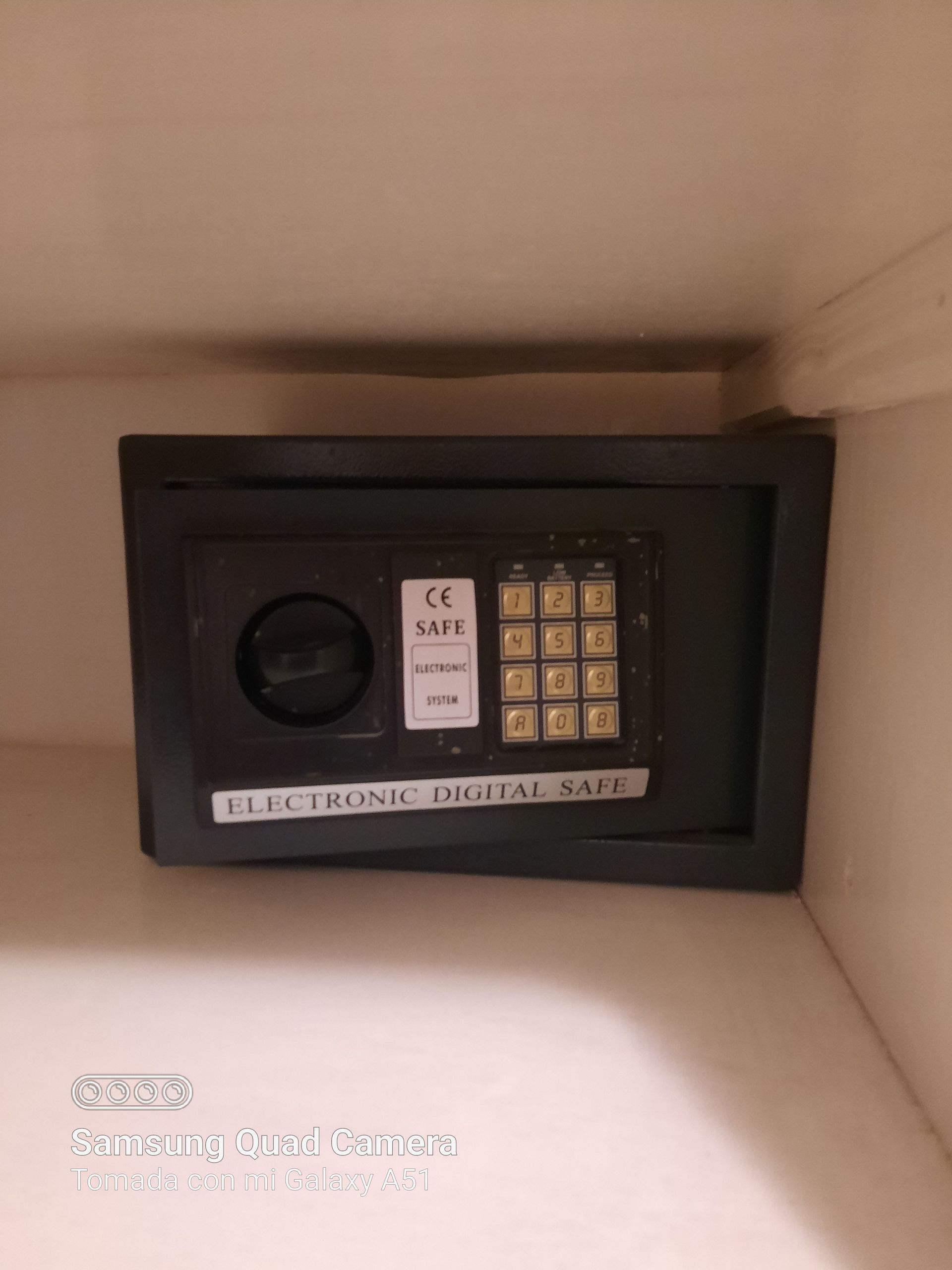 An electronic safe is sitting on a shelf in a room.