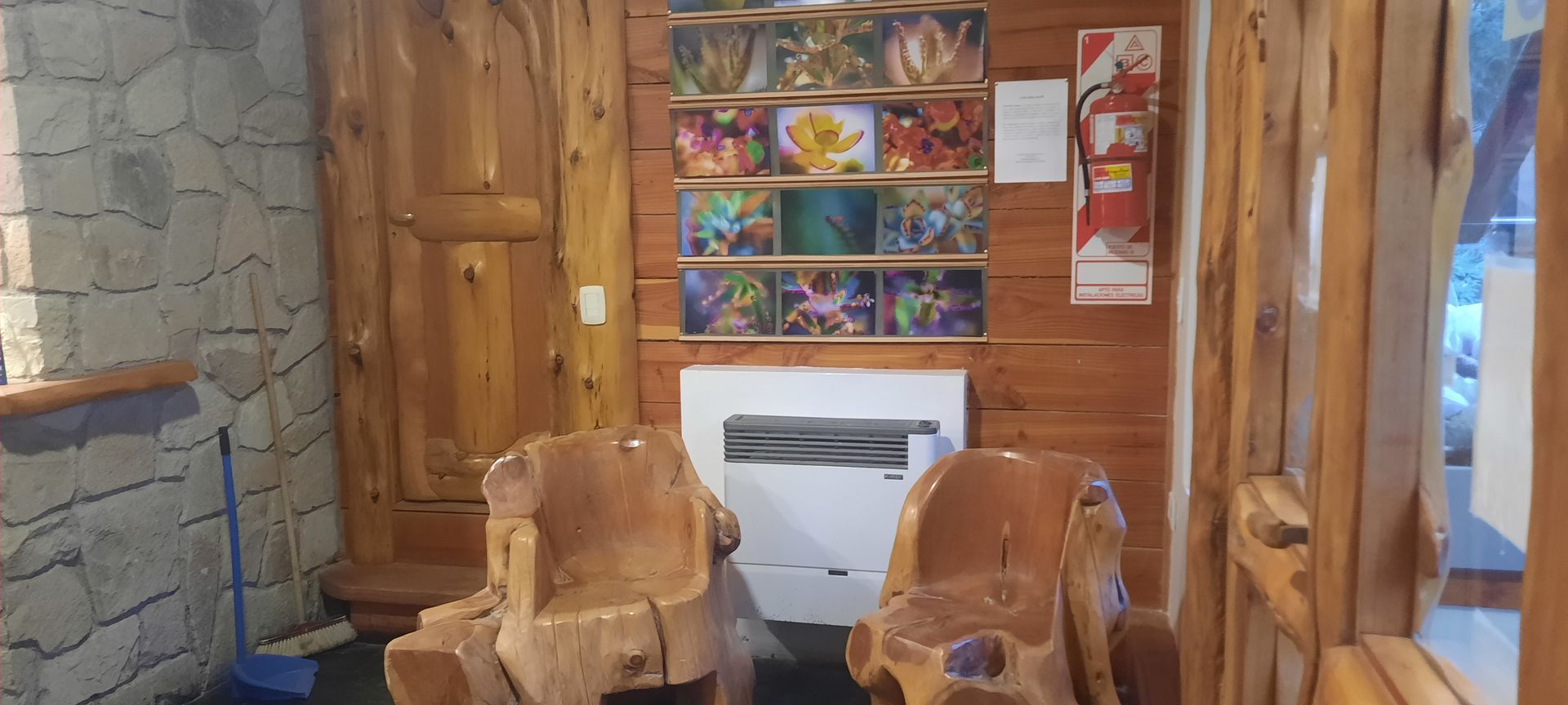 A wooden room with two wooden chairs and a fireplace.