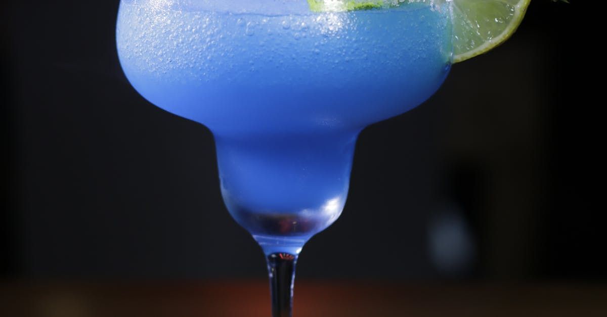 A blue margarita with a lime wedge in a glass on a table.
