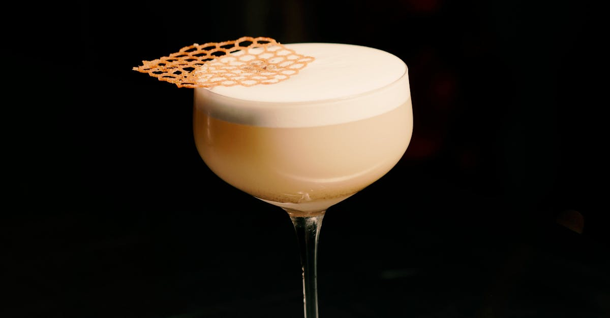 A close up of a cocktail in a wine glass on a black background.
