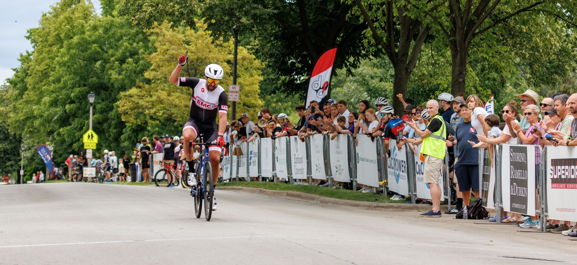 A man is riding a bike down a street in front of a crowd.