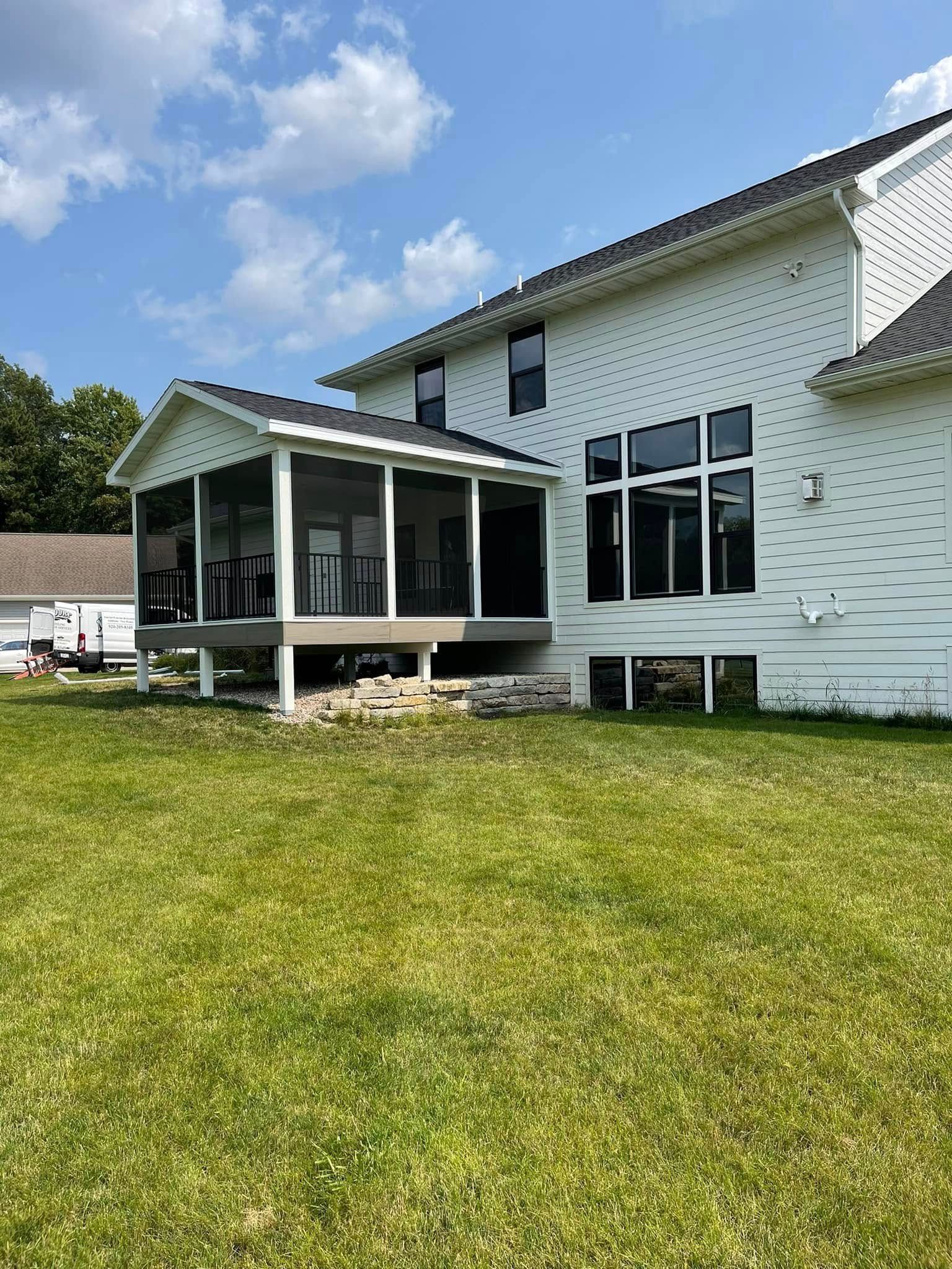 Screened porch attached to a white house with large windows; a grassy lawn.