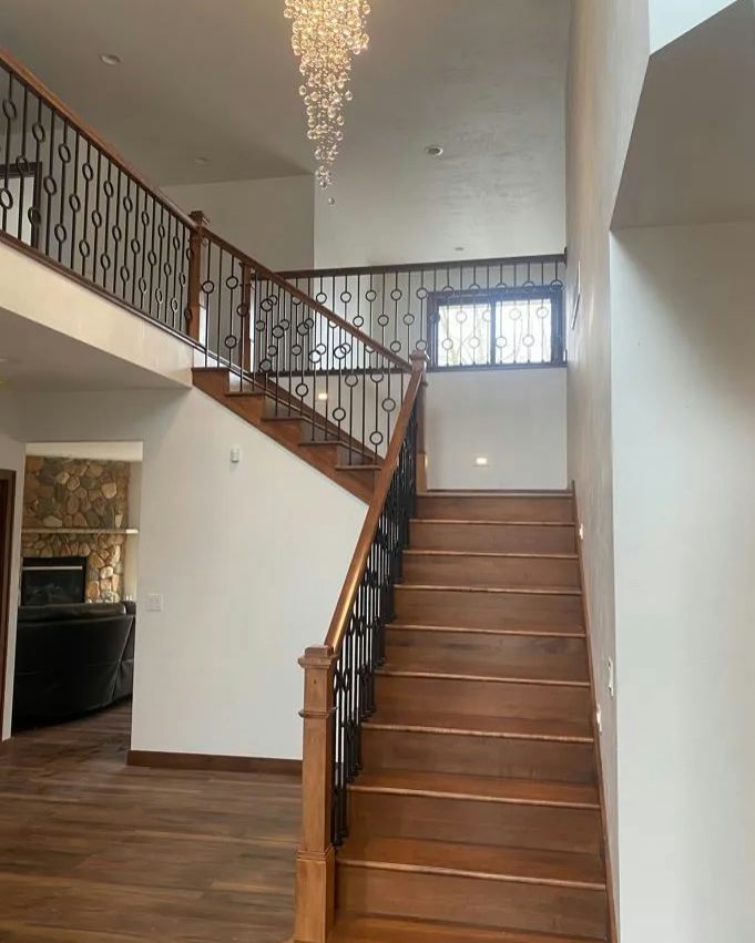 Wooden staircase in a home with a decorative railing and chandelier.