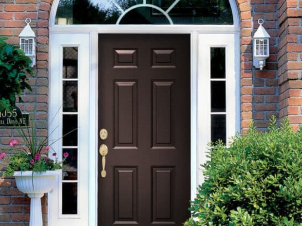 The front door of a brick house with a brown door.