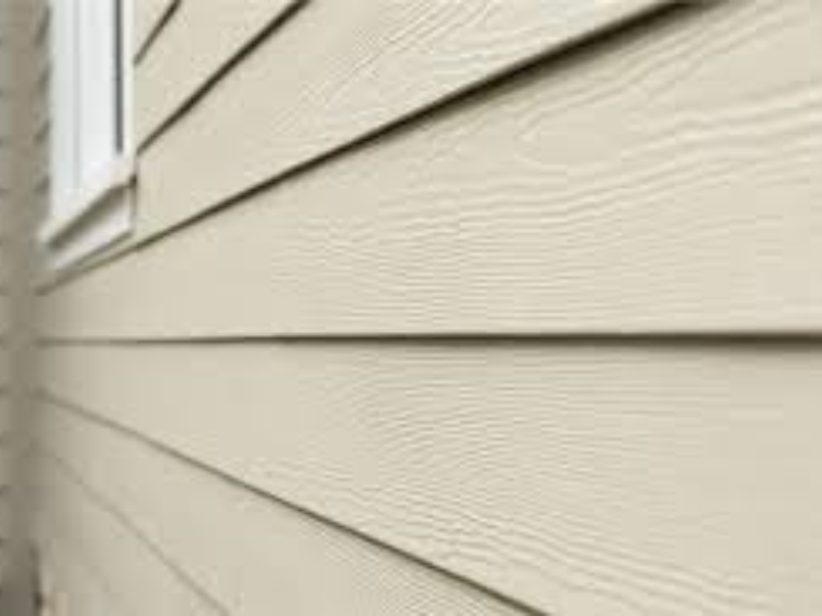 A close up of a beige siding on a house with a window.