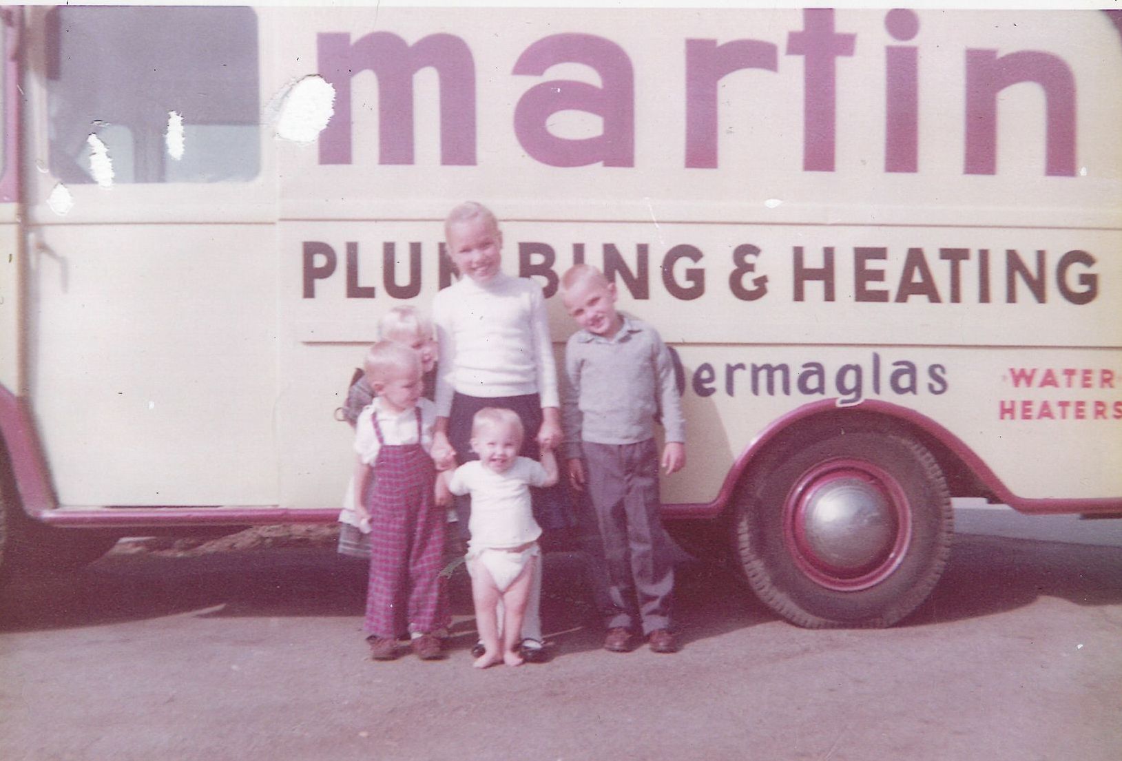 Four children stand in front of a van that says